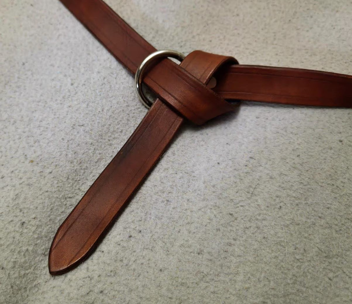 Brown leather belt on a textured beige surface